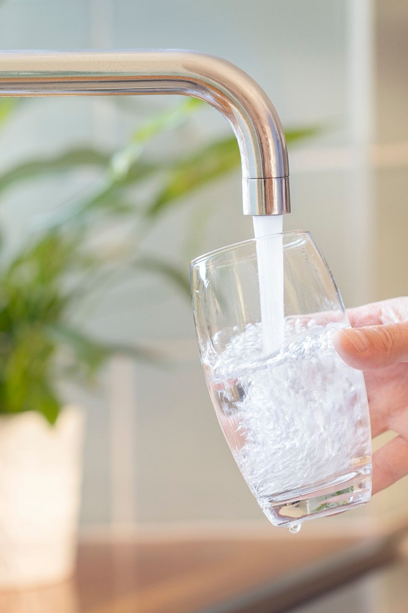 a glass of water being filled under a running tap