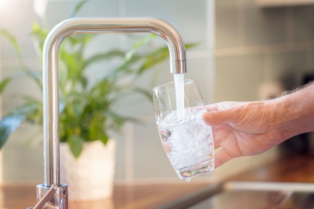 domestic water supply flowing from tap in to a glass held beneath it