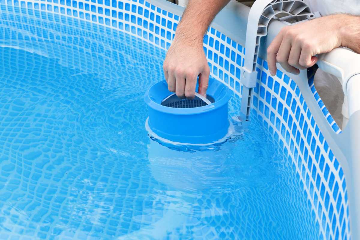 man cleaning the skimmer in a swimming pool