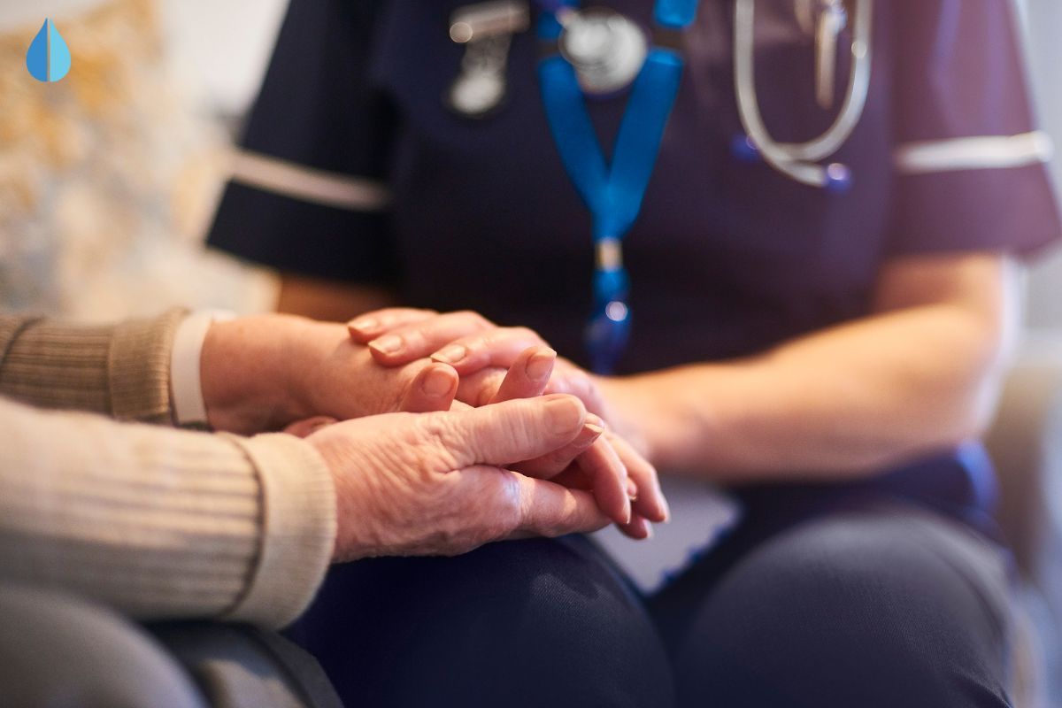 a nurse holding the hand of an elderly person