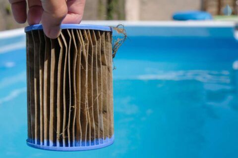 a person holding a filter in front of a swimming pool