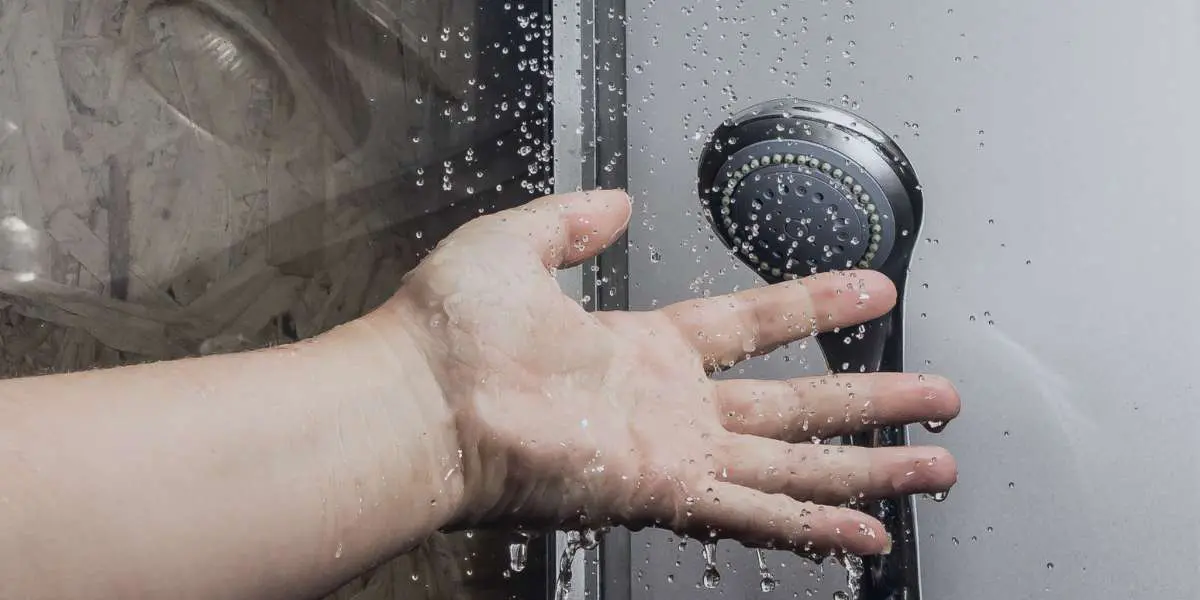 checking shower water temperature with hand