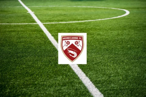 A pristine football pitch overlayed with the badge for Morecambe FC